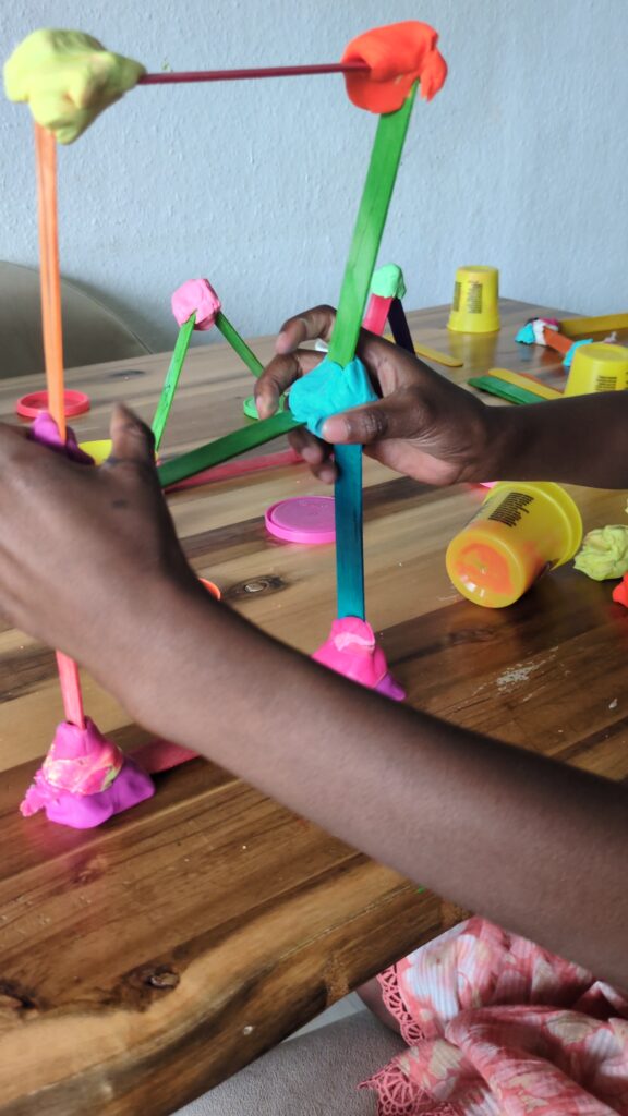 3D geometric shapes and structures built using wooden popsicle craft sticks and small playdough connector balls for a preschool STEAM activity