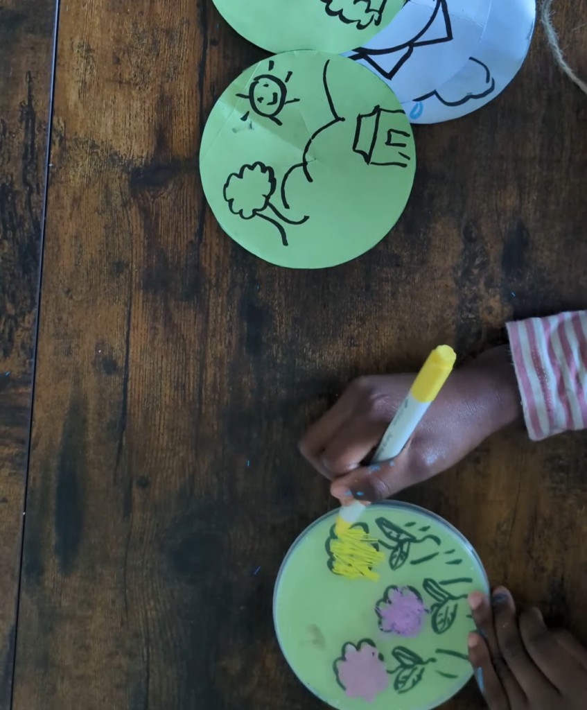 Clear plastic Pringles snack lid used as a reusable DIY dry-erase tracing board with a white paper circle insert for letter practice.