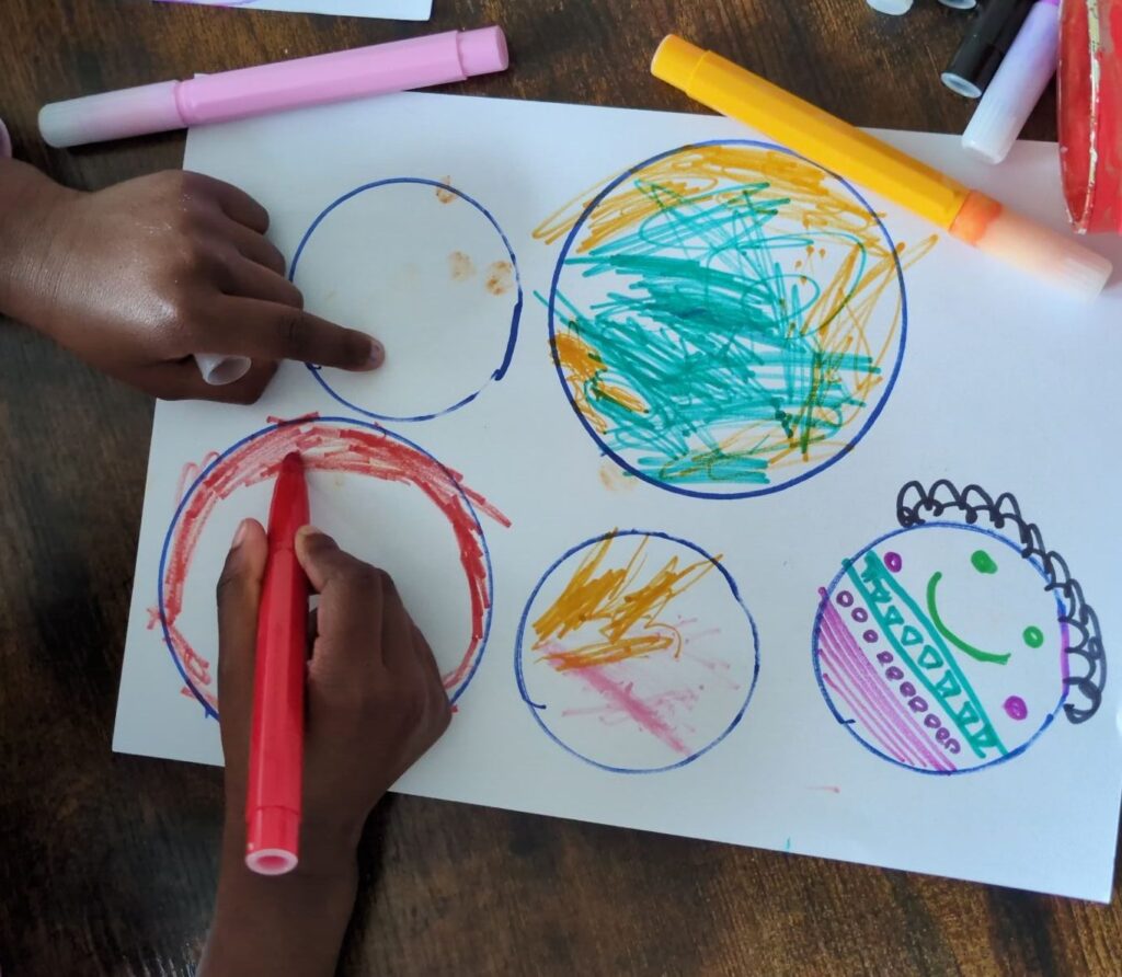 A sheet of white paper with hand-drawn marker circles being turned into creative drawings by a child for an independent play game.